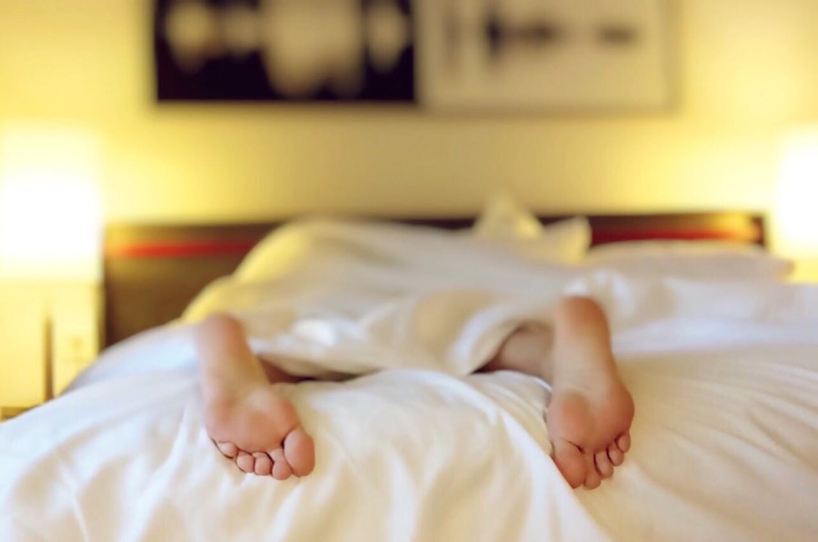 2 Füße schauen unter einer Bettdecke auf dem Bett hervor